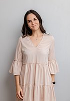 Eine Frau lacht in die Kamera. Sie trägt ein hellrosa Kleid.